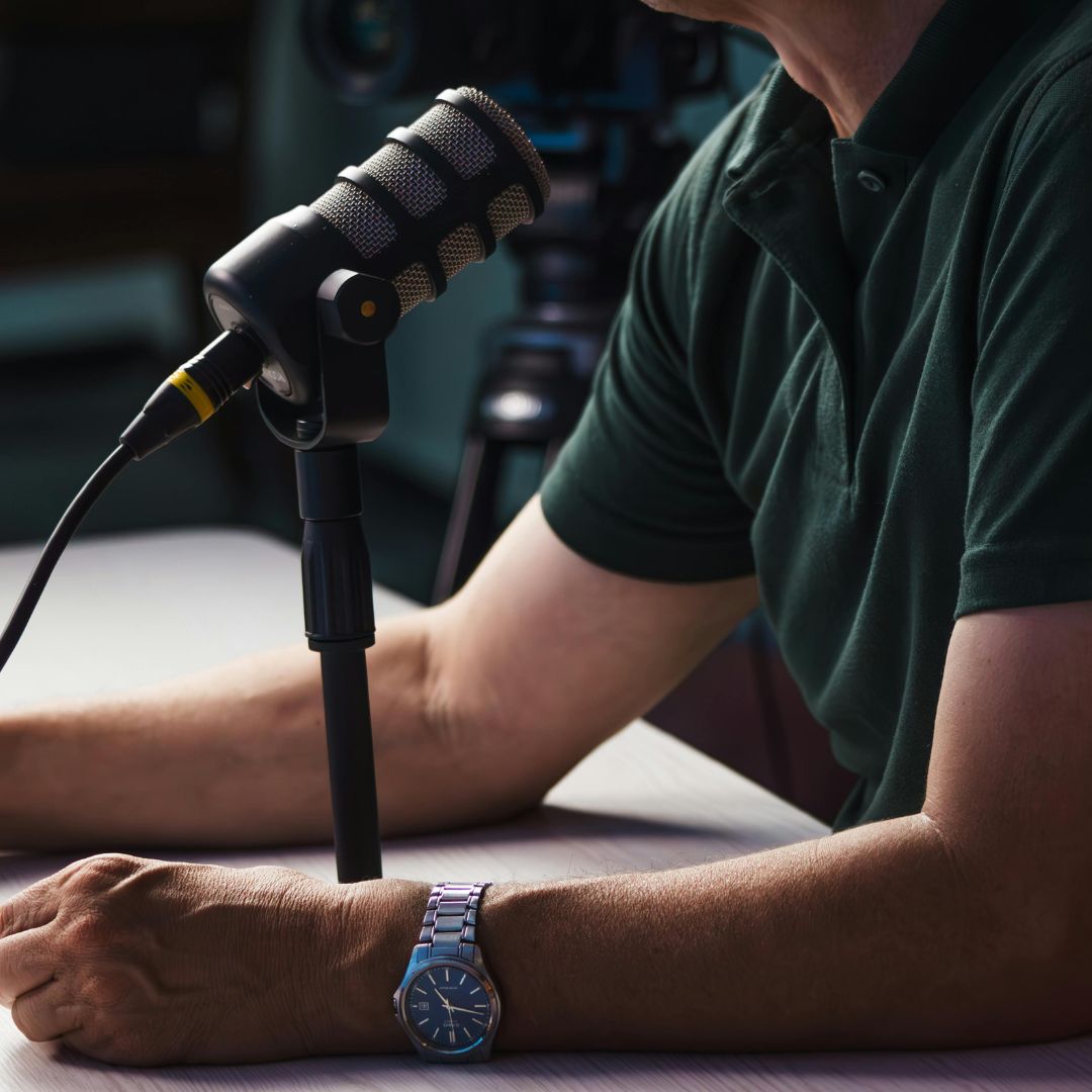 Man die achter podcast micofroon zit aan tafel