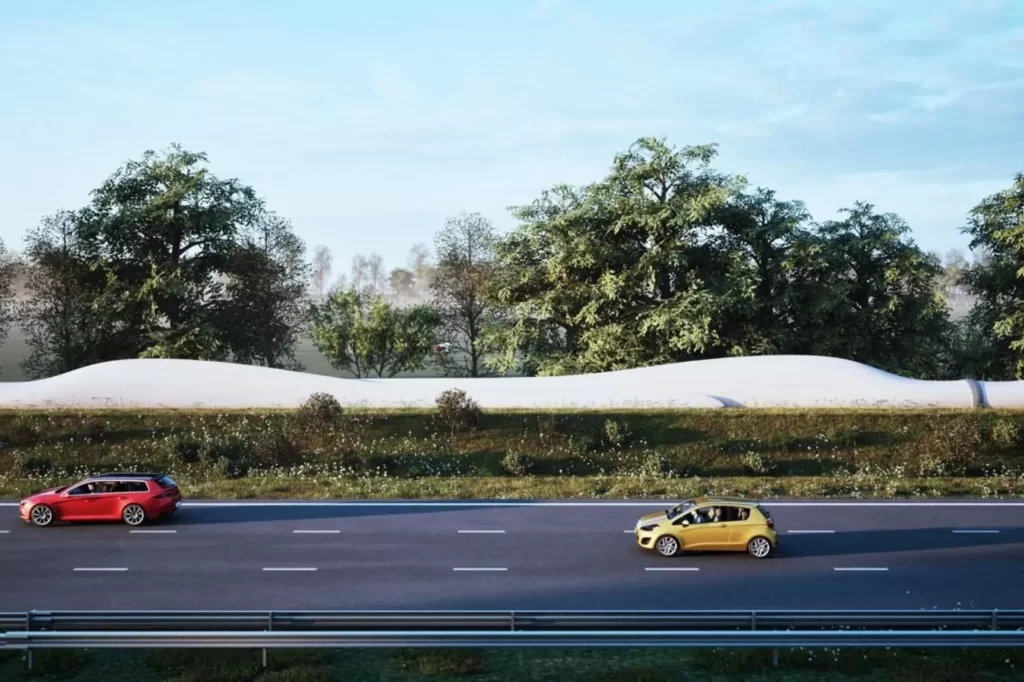 Snelweg met auto's en aan de zijkant afgedankte windmolenbladen die dienen als circulair project