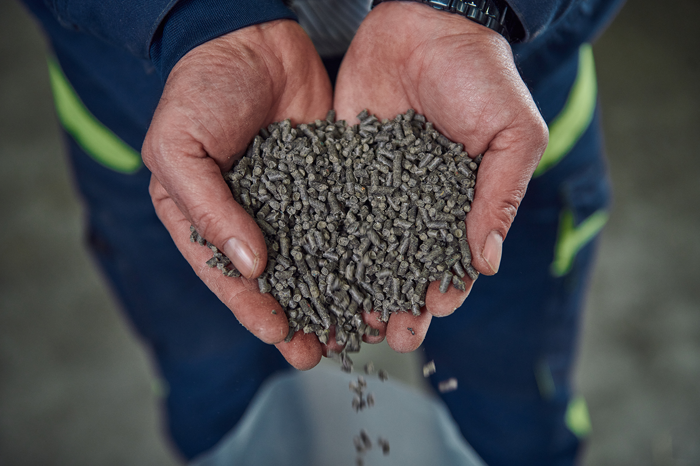Foto met handen waarin gerecyclede korrels composiet van UBQ Materials te zien is. Niet alleen plastic, maar ook organisch afval zoals pizzadozen, bananenschillen en koffieresten is in dit composiet verwerkt. Hiermee kan UBQ Materials allerlei producten maken, zoals auto-onderdelen, bureaustoelen, bouwmaterialen of plantenbakken.